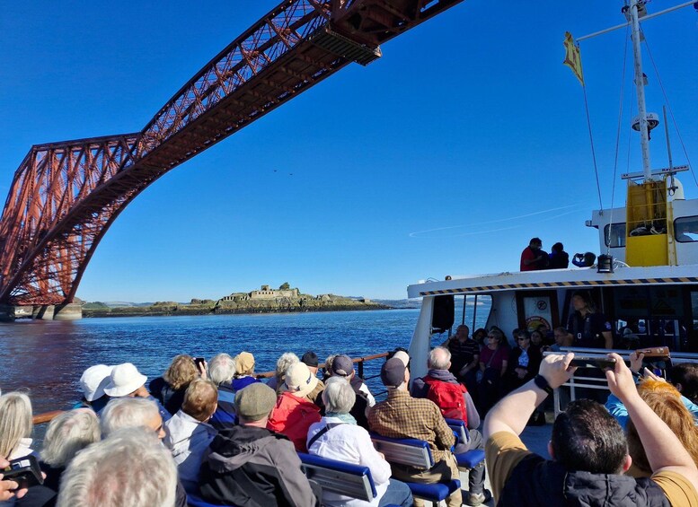 A group of people on a boat observing a large red bridge. 5