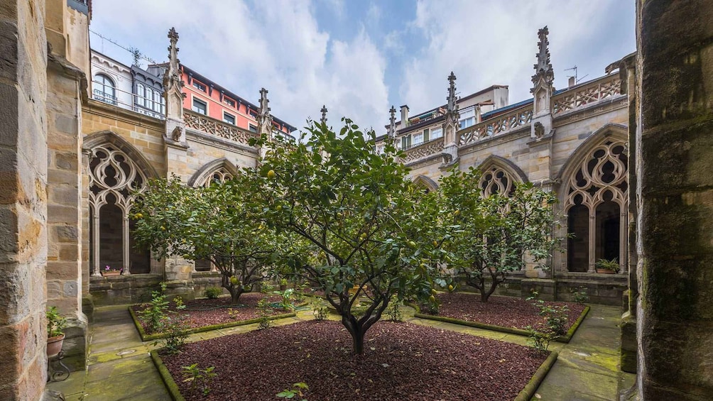 A courtyard with a central tree surrounded by stone walls and arched windows. 3