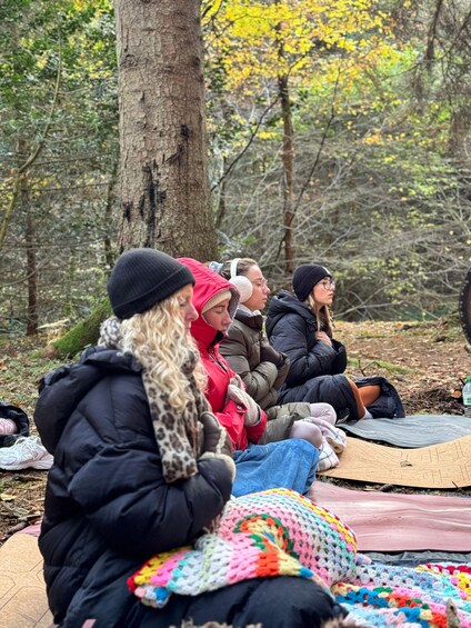 People sitting on blankets in a forest. 2