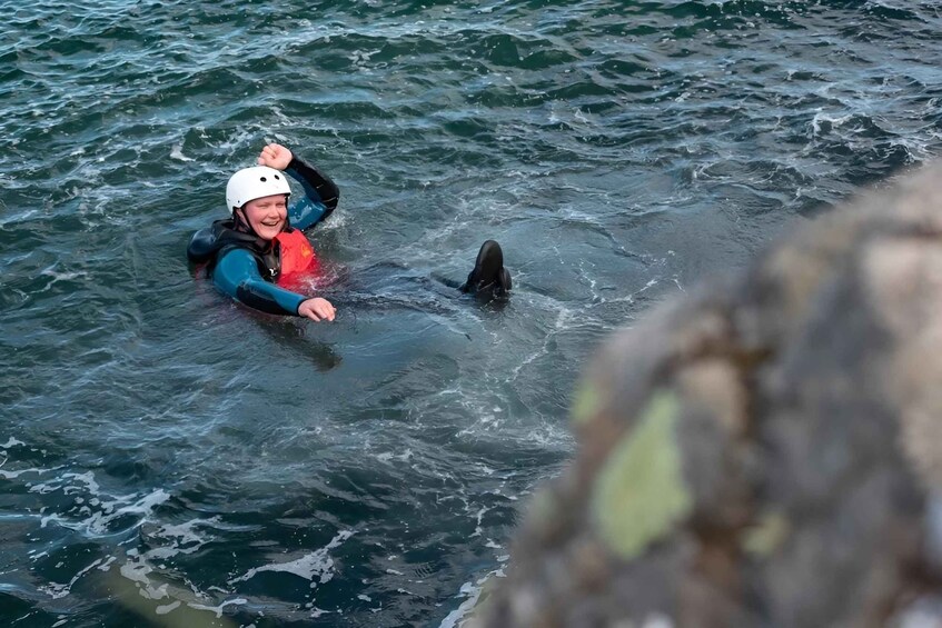 A person in a wetsuit and helmet interacting with a dolphin in the ocean. 4