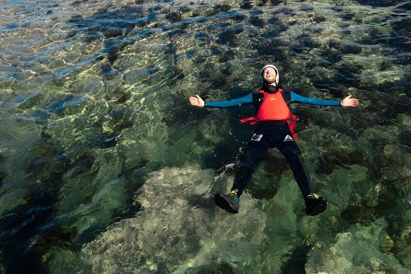 A person floating in clear water with rocks beneath. 3