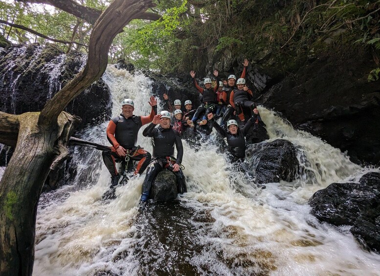 A group of people rafting down a fast-flowing river surrounded by rocky terrain and trees. 1