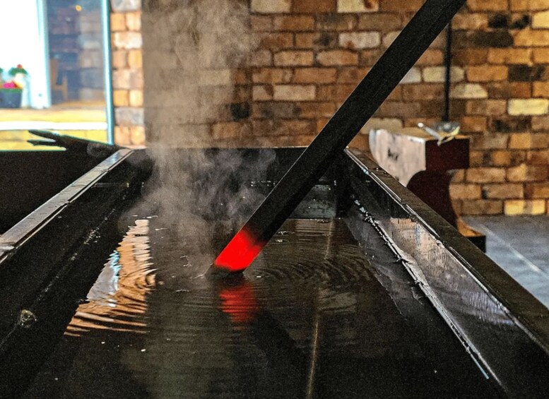 A steam locomotive with a red headlamp emitting steam. 2
