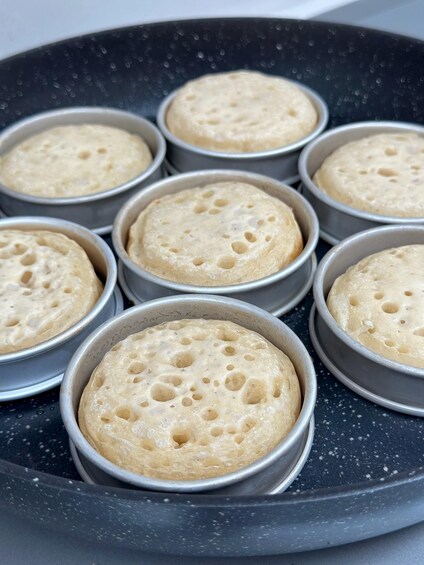 A tray with several round, baked goods in metal containers. 2