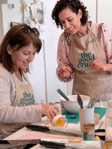 Two people wearing aprons with 'the good crumb' text, preparing food. 4