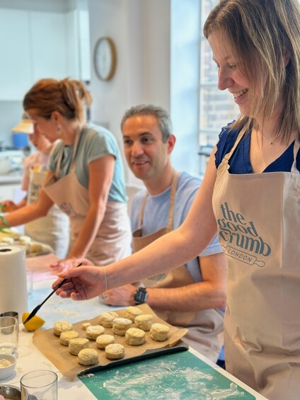 People baking in a kitchen with dough on a tray. 3