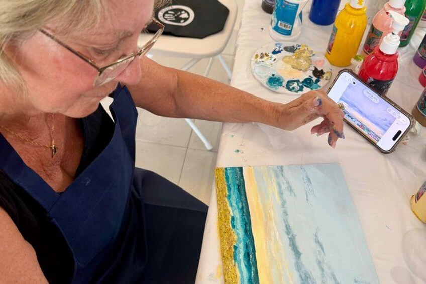 A person painting a landscape with a smartphone nearby. 3
