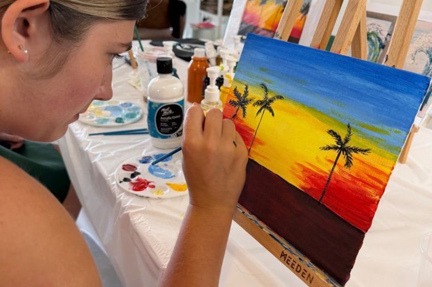A person painting a sunset scene with palm trees. 1