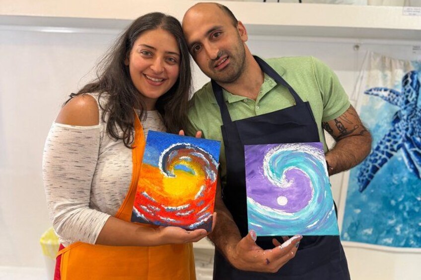 Two people holding painted canvases with swirling patterns. 2