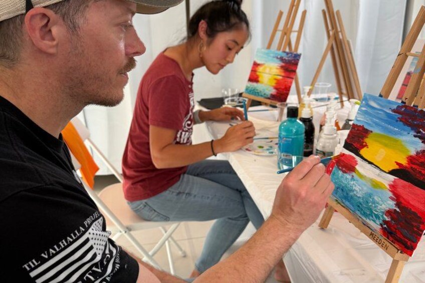 A person painting on a canvas with a palette of colors. 4