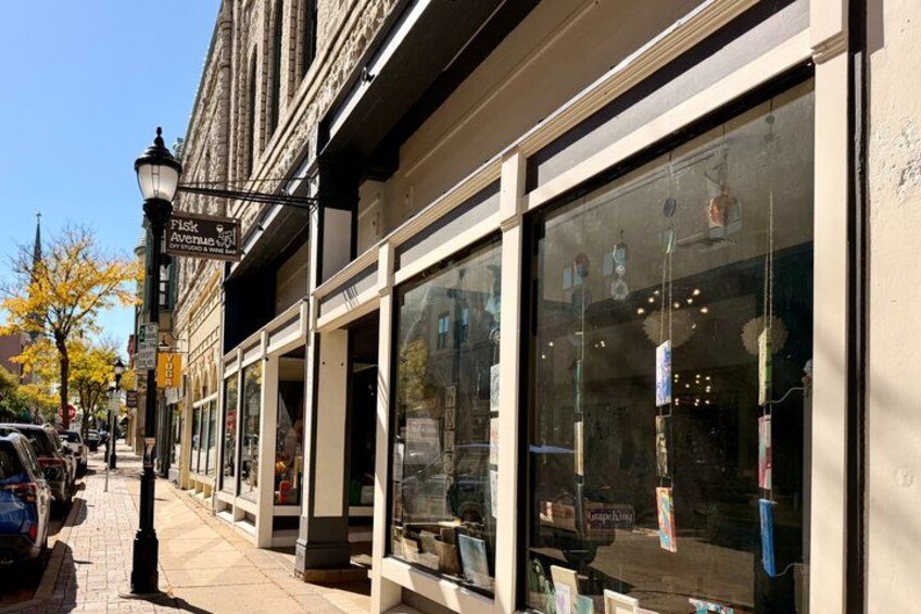 A street with storefronts, parked cars, and a clear sky. 2