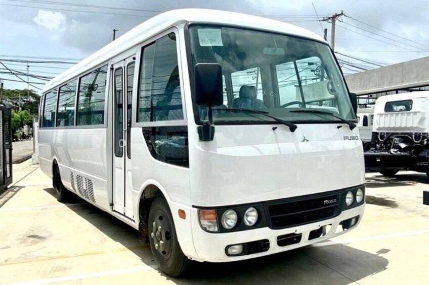 A white bus parked in a lot with other vehicles. 1