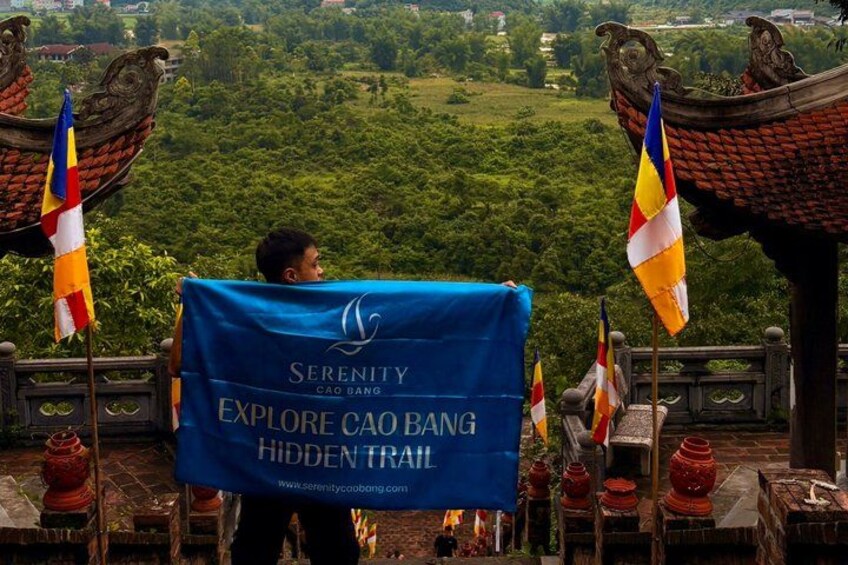 A person holding a banner with text, flags, and traditional architecture in the background. 1