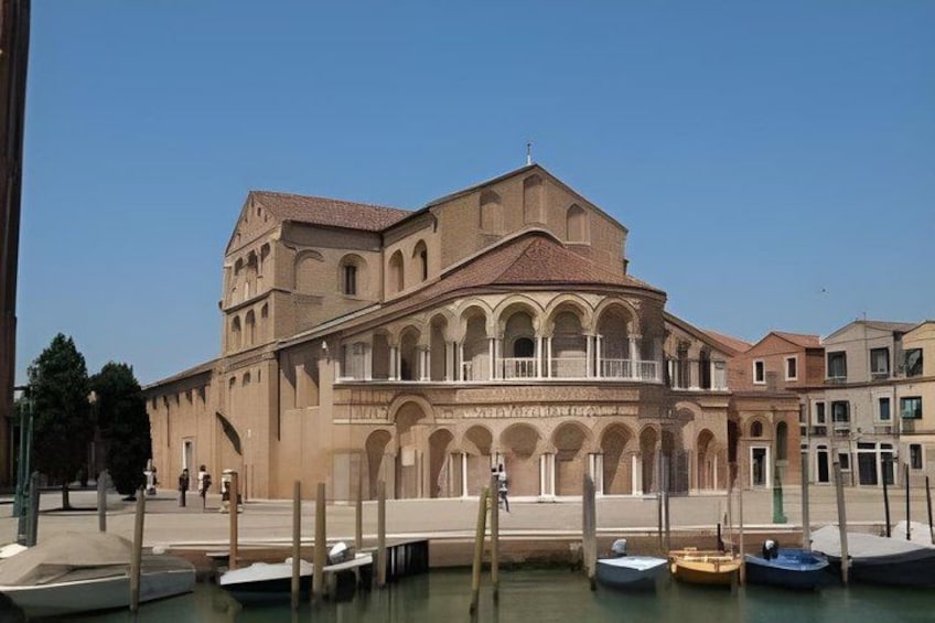 A historic building with a central dome and arched windows, surrounded by a canal with boats. 5