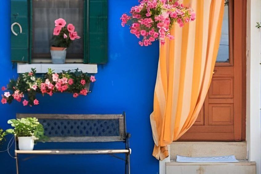 A blue wall with a wooden bench, a window with green shutters, and a door with a striped curtain. 3
