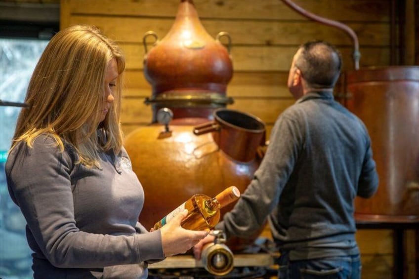 A person pouring liquid from a large copper vessel into a smaller container. 5
