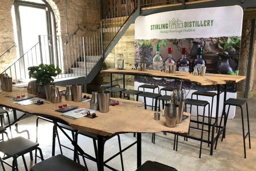 A distillery bar with a wooden table, metal chairs, and a staircase. 4