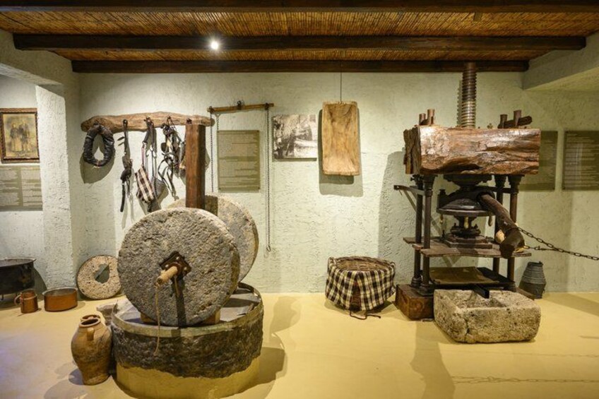 A historical exhibit with stone millstones, wooden tools, and a wooden press. 1