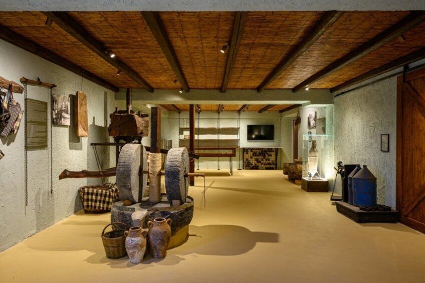 A rustic interior with stone structures, wooden beams, and various artifacts on display. 5