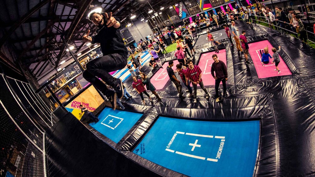 En indendørs trampinpark med mange trampoliner og folk der hopper. 2