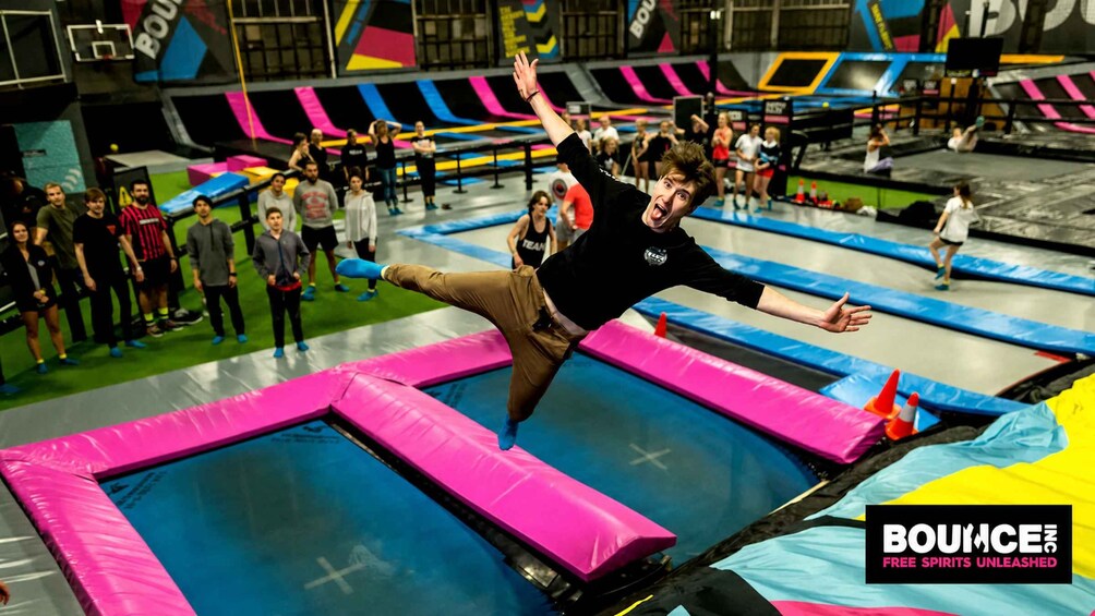 En trampolinpark med flere trampoliner og folk, der hopper. 1