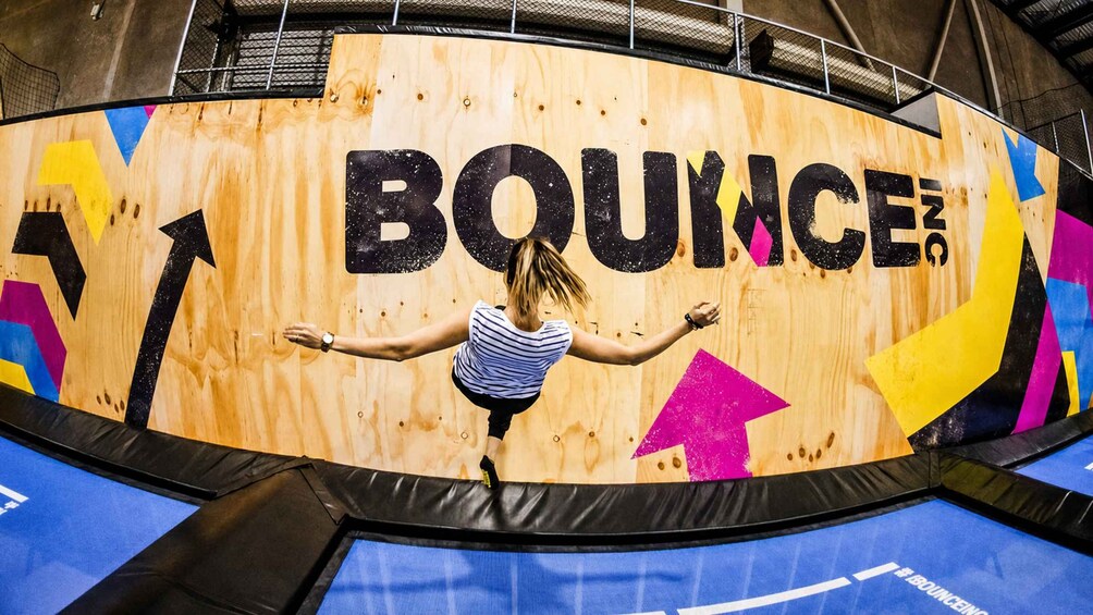 A trampoline with a wooden wall featuring the word 'BOUNCE' and colorful geometric shapes. 5