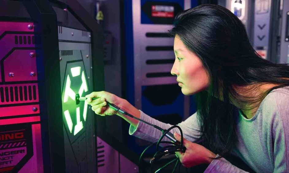 A person using a tool on a machine with a green light. 5