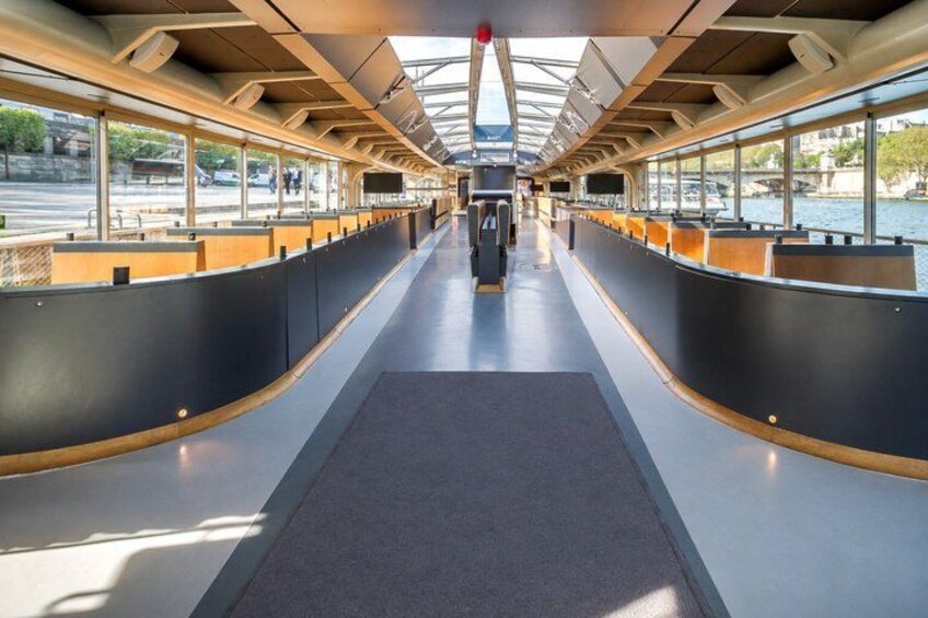 A modern boat interior with a central aisle, seating on both sides, and large windows. 2