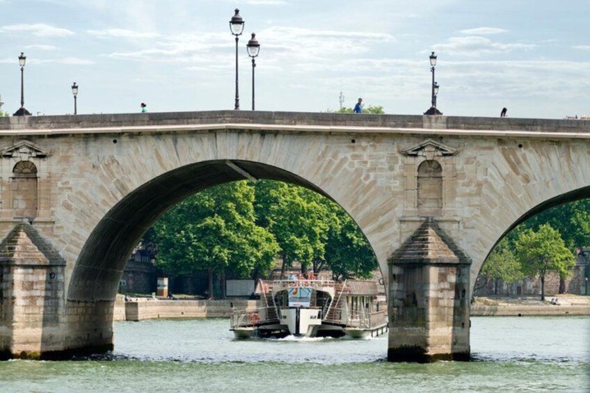 A stone bridge with three arches over a river, with a boat and a small building in the background. 5