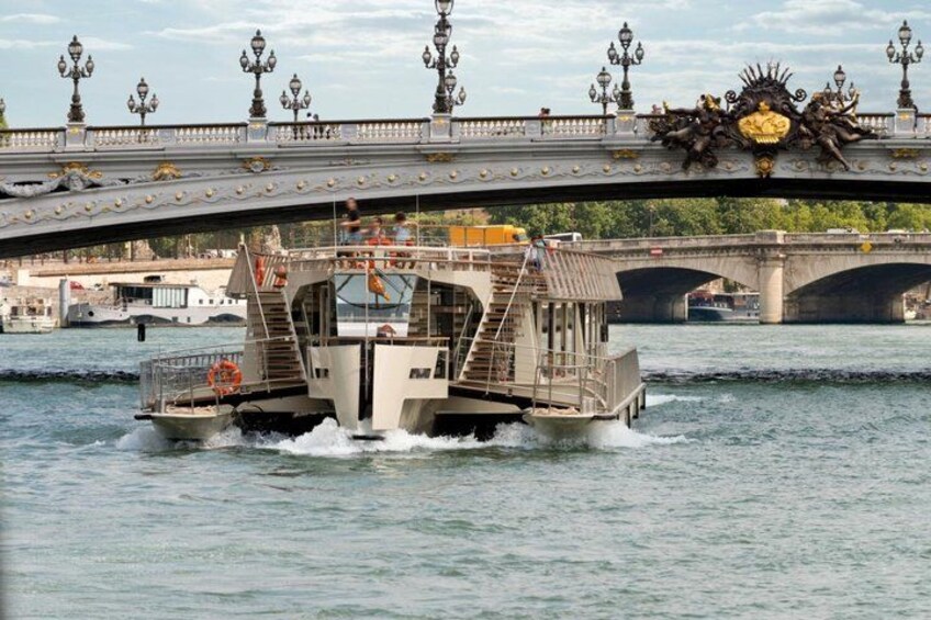 A boat on a river under a bridge with ornate lamp posts and a decorative crest. 4