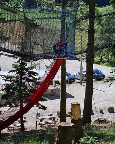 A playground with a red slide, a netted climbing structure, and a picnic area. 2