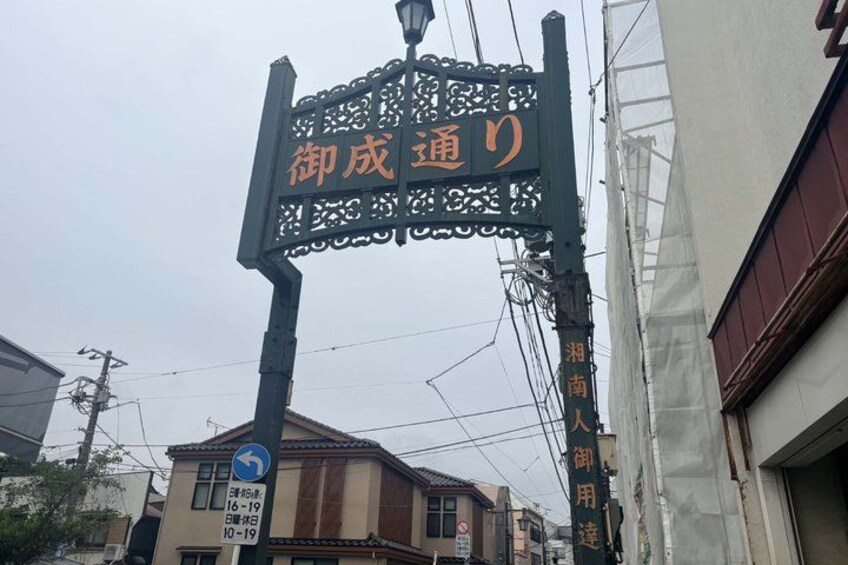 A street sign with Japanese characters, a directional arrow sign, and a building with a visible entrance. 3