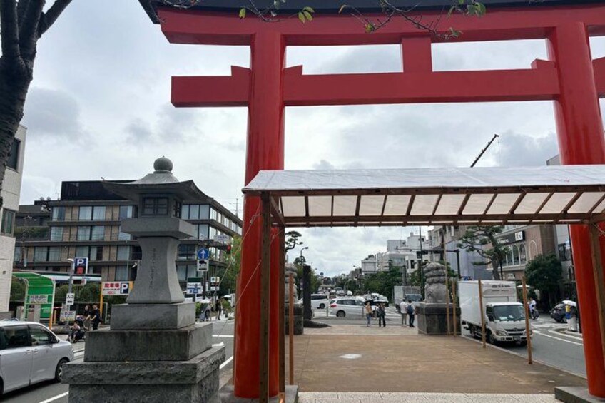 A red torii gate, a stone monument, and a busy street with buildings and vehicles. 4