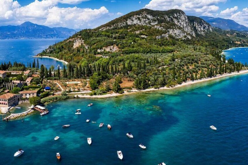 A coastal landscape with clear turquoise waters, boats, and a mountainous backdrop. 2