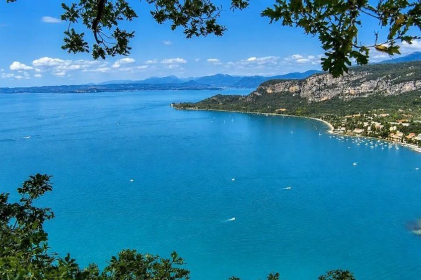 A coastal landscape with clear blue waters, a curved shoreline, and distant mountains. 4
