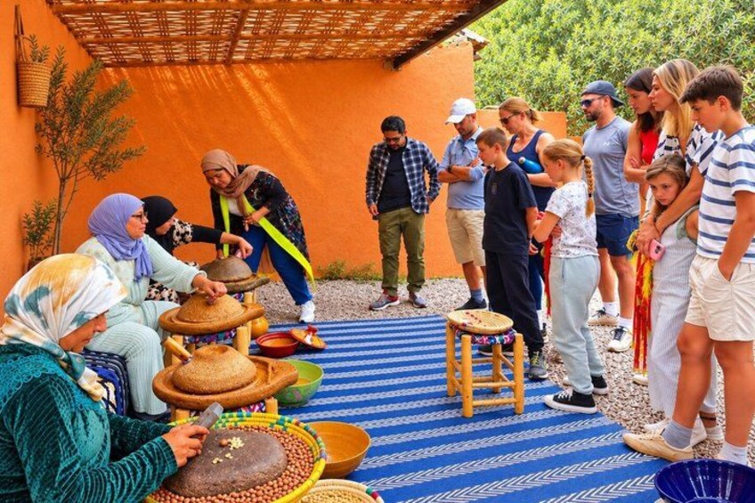 A group of people engaged in a traditional activity, possibly a cultural demonstration, with pottery and bowls on a blue patterned mat. 5