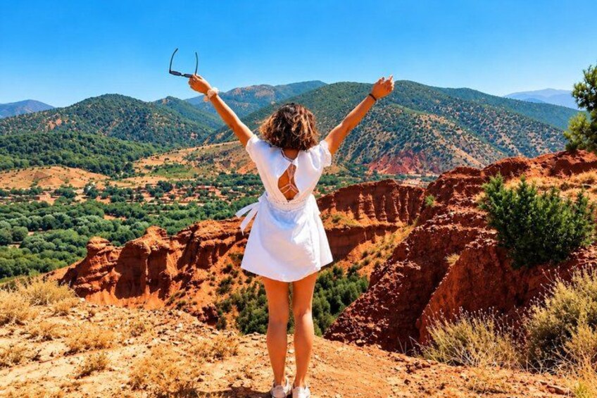 A person standing on a hill with arms raised, overlooking a mountainous landscape. 4