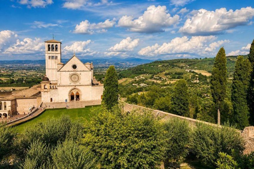 A historic church with a bell tower, surrounded by lush greenery and rolling hills. 3