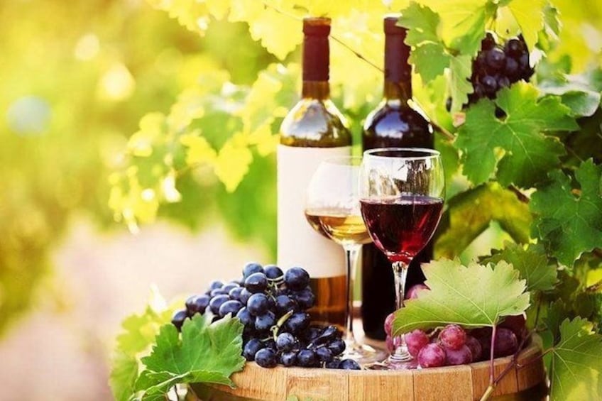 A wooden barrel with grapes, two wine bottles, and a wine glass. 2