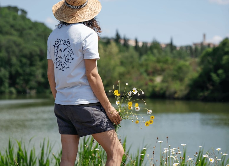 Une personne se tient près d’un lac, tenant des fleurs. 3