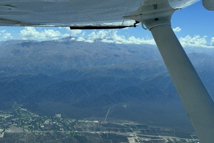 An airplane wing, a mountainous landscape, and a city below. 2