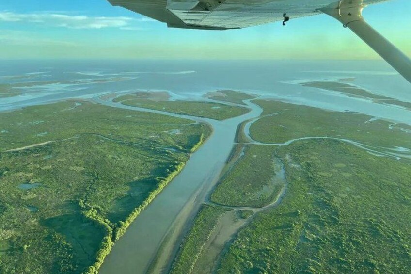 An aerial view of a river winding through a green landscape with a clear sky. 1
