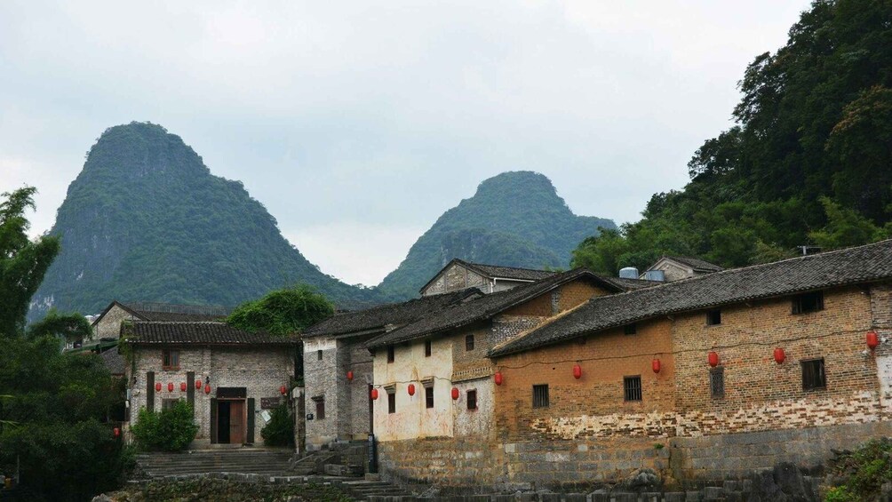 Traditional buildings with red lanterns, set against a backdrop of lush green mountains. 2