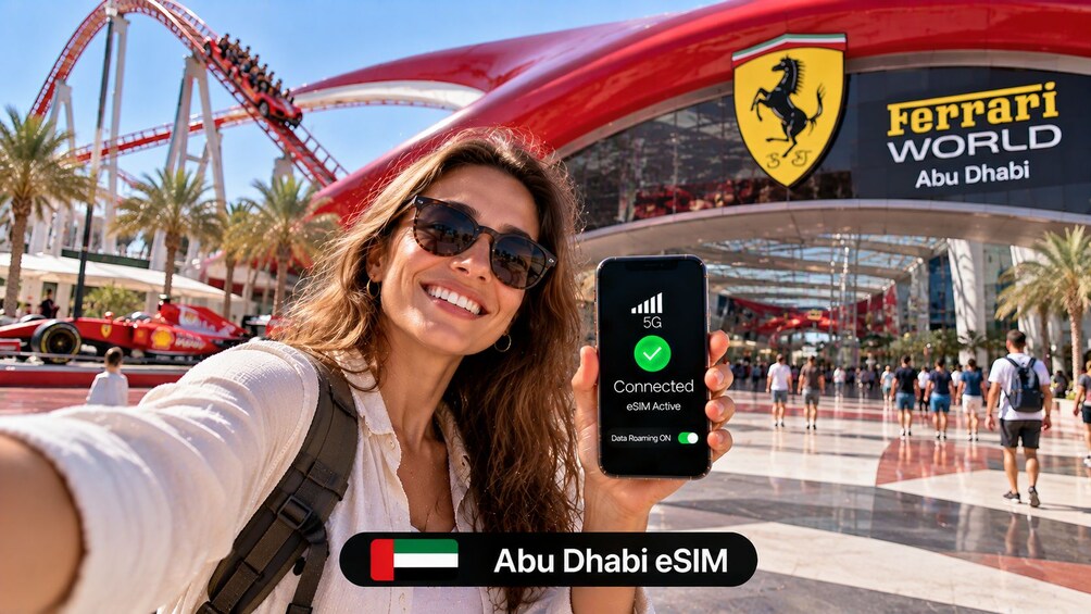 A person holding a smartphone displaying a 5G connection status in front of a Ferrari World sign. 1