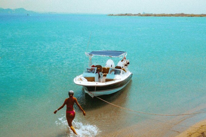 A woman in a swimsuit walking towards a boat on a calm body of water. 4