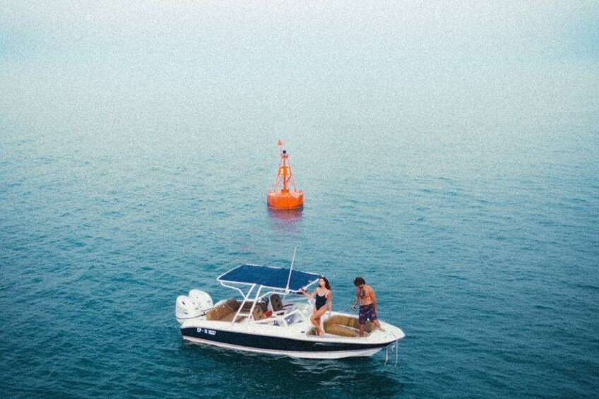 A boat with two people on it, a lifebuoy, and a buoy in the water. 2