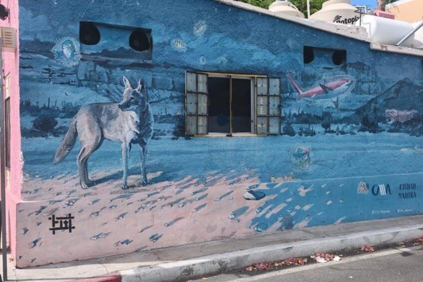 A mural with a wolf, a shark, and marine life on a building. 2