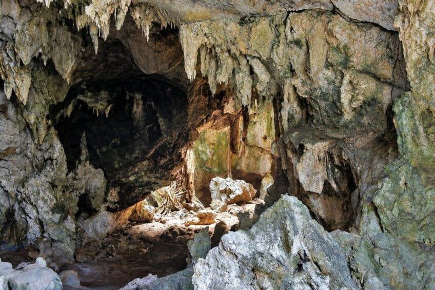 A cave with stalactites and stalagmites, rocky formations, and a water pool. 3