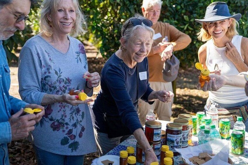 A group of people at an outdoor gathering with a table full of food and drinks. 4