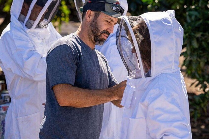 A person in a dark shirt and protective suit interacting with another person in a white protective suit. 2
